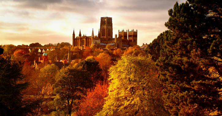 View of Durham Cathedral and city surrounded by autumn colour trees.